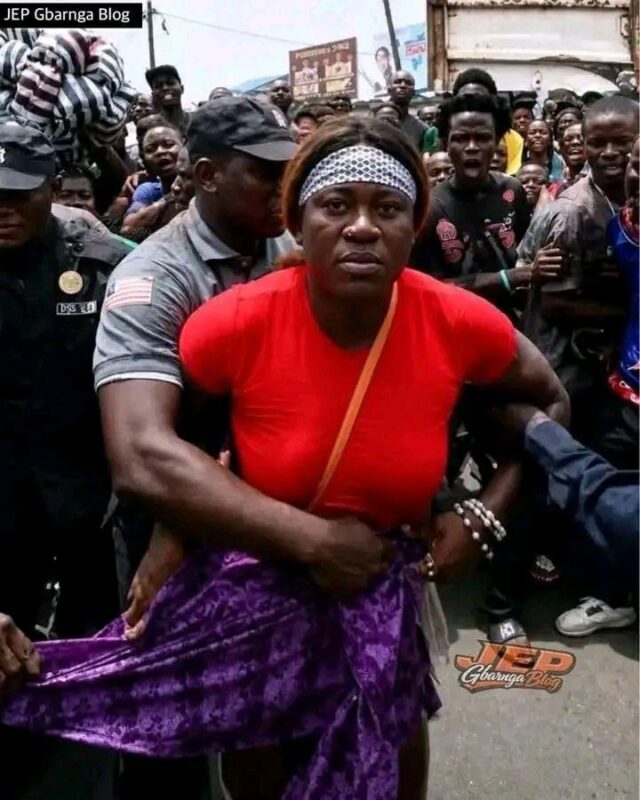 Paynesville City Police Officer Augustine T. Musa helping to cover the naked body of Grace who was harrassed and touted by mob